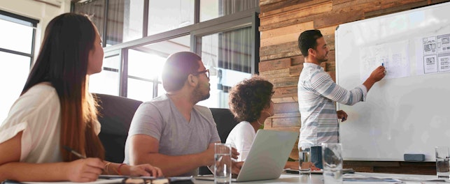 Shot of a male office worker giving creative presentation to his colleagues. Businessman explaining business plan to coworkers in conference room.